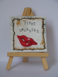 mixed media, assemblages van handwerk en readymades
De kusjes van klei zijn bevestigd op een klein beschilderd doekje, de gestempelde tekst en het miniatuur ezeltje maken het helemaal af.