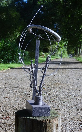 sculpture with wire overlooking dirt-road