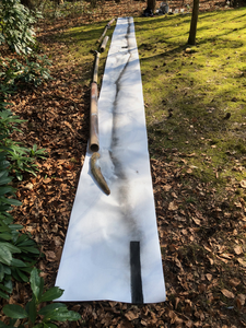 Beschilderd behang, uitgerold over gras in een tuin vol bomen, nodigt bezoekers uit tot het schrijven van een boodschap ...