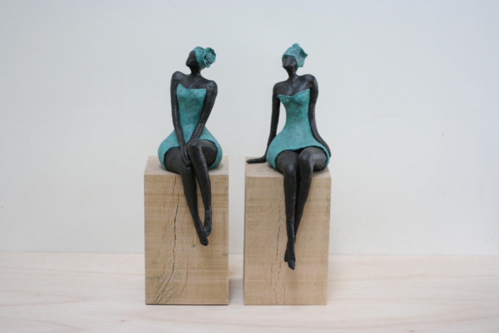 Keramiek beeldje van donkere relaxte slanke dame met bloem (links)