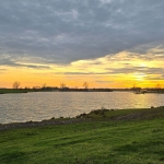 Ondergaande zon over de rivier de Maas