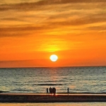 Mensen aan zee met ondergaande zon