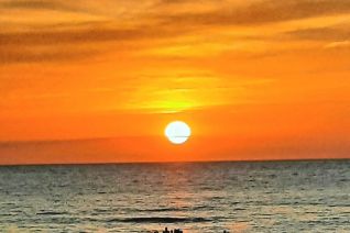 Mensen aan zee met ondergaande zon