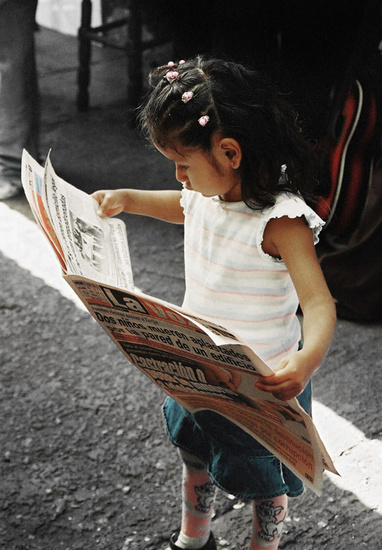 Little girl reads newspaper in Bolivia