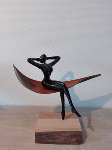 Het figuurtje zit op een blad en balanceert op de teen op een prachtig blok hout. 
In overleg zijn ook andere houdingen mogelijk.