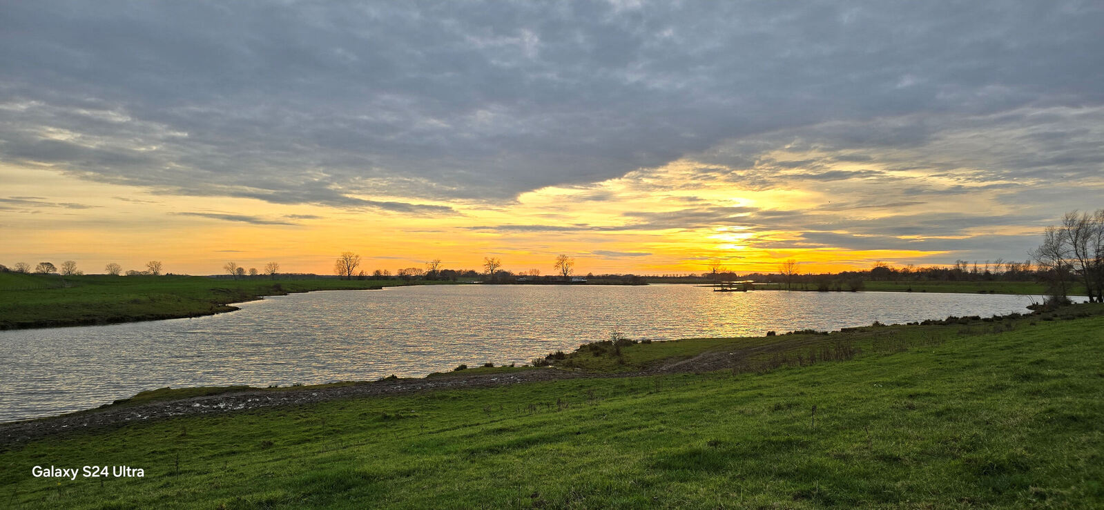 Ondergaande zon over de rivier de Maas