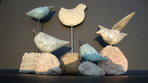 Gestileerde vogelvormen, gebakken met de traditionele RAKU methode (een oude Koreaanse techniek uit de 16de eeuw), door het rookproces ontstaat de kenmerkende zwarte craquelé in het glazuur en de zwarte kleur van de klei.
De vogels worden gepresenteerd op een metalen pen of direct op een natuurstenen voet.