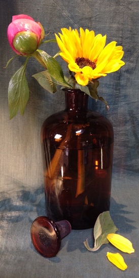 Zonnebloem en pioenroos in apothekersfles