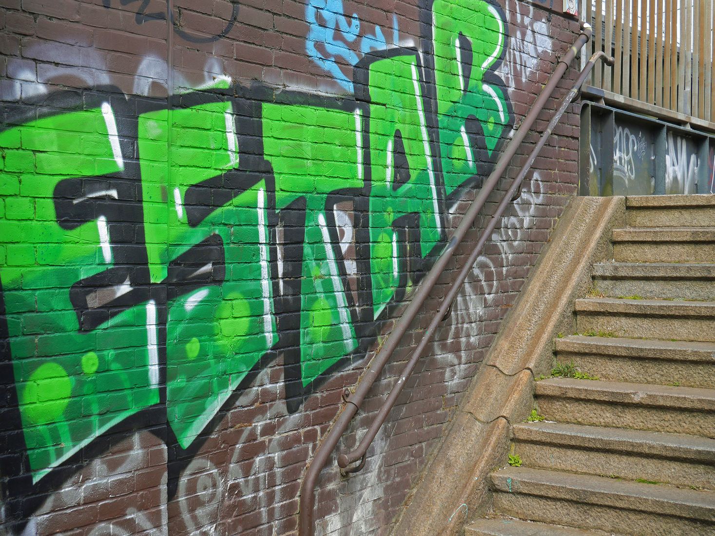 Grote graffiti-tag in groene letters bij de loopbrug over de Nieuwe Vaart; foto Amsterdam / Mokum.
