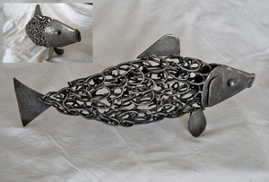 Fijn smeedwerk. Gebruikte spijkers vormen de basis van dit pronkstuk; de kop en de vinnen zijn uit cortenstaal vervaardigd.