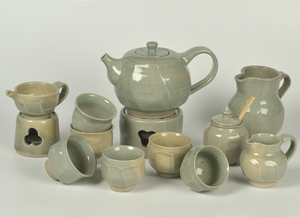 Theepotten, rechauds, theekopjes, melkkannetjes en suikerpotten met facetten en gedraaid op de draaischijf. Geglazuurd met oude Chinese celadon glazuren. Gestookt in de gasoven (steengoed) op 1240 graden. Unieke stukken in de 'de kleur van de hemel na een regenbui'.